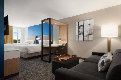 SpringHill Suites by Marriott Milwaukee West/Wauwatosa في اوواتوسا: غرفه فندقيه بسرير واريكه