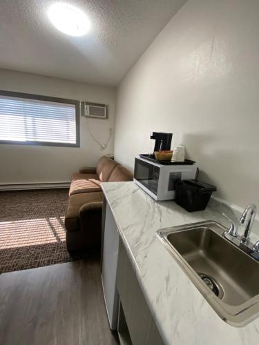 a kitchen with a sink and a couch in a room at Super 8 by Wyndham Penticton in Penticton