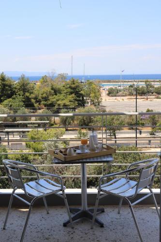 a table and chairs on a balcony with a view of a field at IKAROS Hotel ELLINIKO in Athens