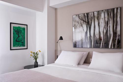 アテネにあるParthenon Apartmentの白いベッドルーム(ベッド1台付)が備わります。壁には絵画が飾られています。