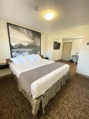 a bedroom with a large bed with a large painting on the wall at Super 8 by Wyndham Penticton in Penticton
