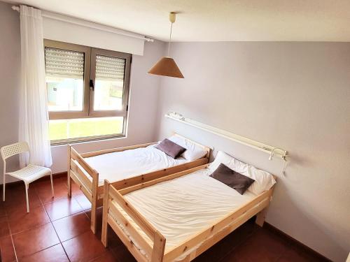 two beds in a room with a window at Apartamentos San Vicente Playa in San Vicente de la Barquera