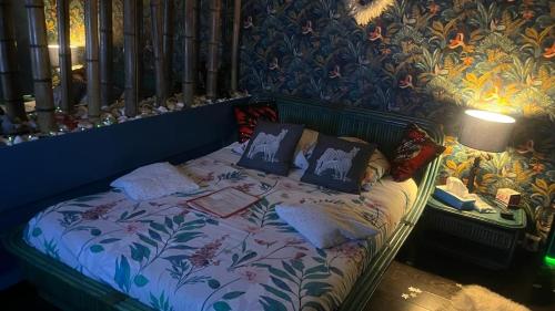 uma cama num quarto com uma parede estampada floral em SPABYELLEETLUI spa rouge ou bleu em Mouscron