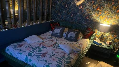a bed in a room with a floral patterned wall at SPABYELLEETLUI spa rouge ou bleu in Mouscron