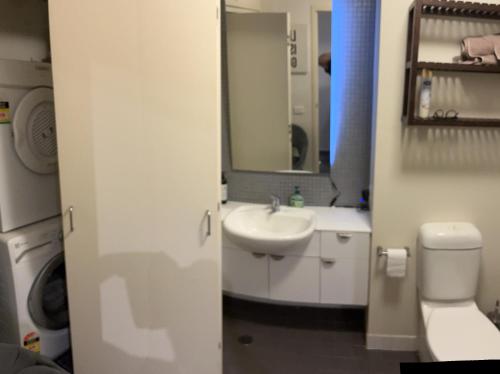 a bathroom with a sink and a toilet and a mirror at The One Grand Prix Living in Melbourne