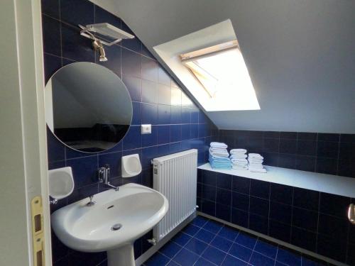 a blue tiled bathroom with a sink and a mirror at Attico Chiavari in Chiavari