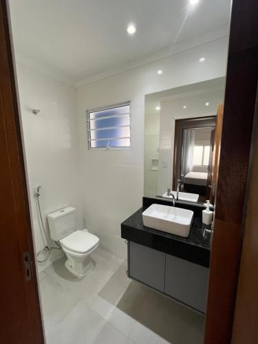 a bathroom with a toilet and a sink and a mirror at Casa Cozy - Excelente Localização in Piracicaba