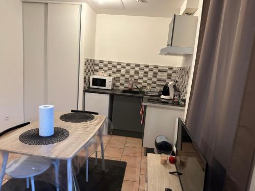 a small kitchen with a table and a microwave at Chez doudou in Roanne