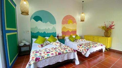 a bedroom with two beds and a mural on the wall at Hotel campestre La Esperanza en Dios in Montenegro