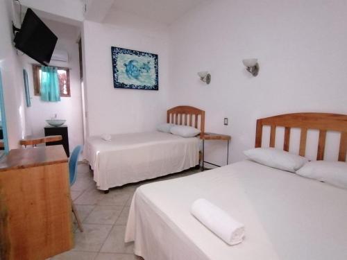 a hotel room with two beds and a television at Casa Tortuga Azul in Palenque