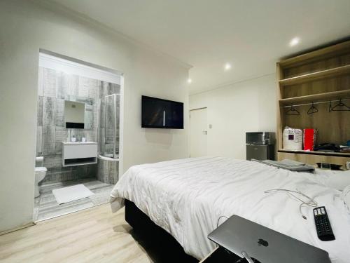 1 dormitorio con 1 cama grande y baño en Stay In Carlazo - Unlimited WiFi, Solar backup, en Roodepoort