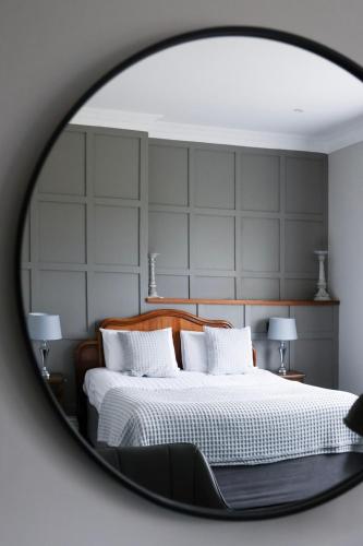 a mirror reflecting a bed with white sheets and pillows at Cantley House Hotel - Wokingham in Wokingham