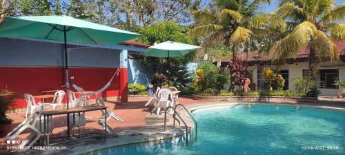 a pool with a table and chairs and an umbrella at Poseidon Guest House in Iquitos