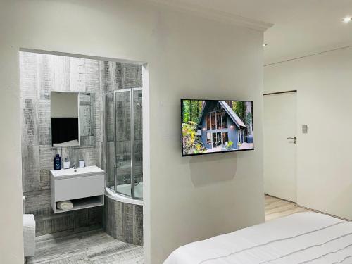 1 dormitorio con baño y TV en la pared en Stay In Carlazo - Unlimited WiFi, Solar backup, en Roodepoort