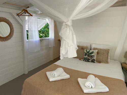 um quarto com duas toalhas numa cama com uma janela em GWO CAILLOU - Gites créoles de charme em Bouillante