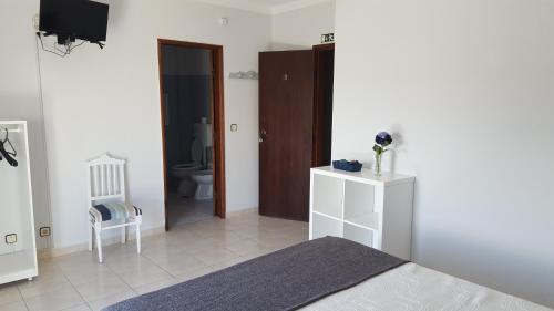 a bedroom with a bed and a bathroom with a toilet at Alojamento Dona Inês de Castro in Atouguia da Baleia