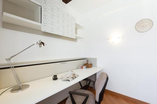 einen weißen Schreibtisch mit einer Lampe und einem Stuhl in der Unterkunft Casa del Borgo - Esclusiva Suite centro Monza con vista Duomo in Monza