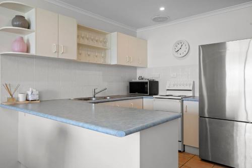 a kitchen with white cabinets and a stainless steel refrigerator at Apartment 9T in Lennox Head
