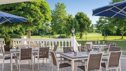 a patio with tables and chairs and umbrellas at Dorint MARC AUREL Spa & Golf Resort in Bad Gögging