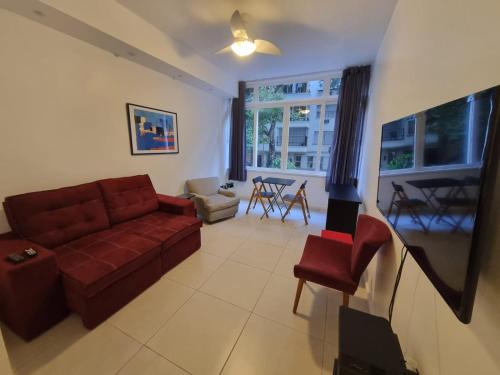 Apartamento Copacabana: aconchego, conforto, privacidade في ريو دي جانيرو: غرفة معيشة مع أريكة حمراء وطاولة