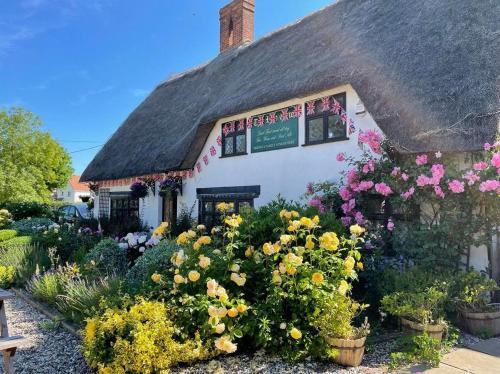 a cottage with flowers in front of it at The Red Cow in Heydon