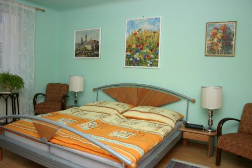 a bed in a bedroom with two chairs and paintings at Ferienwohnung Marie in Vienna