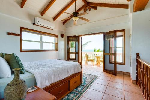 a bedroom with a bed and a patio with a table at Villa 99-Beachfront-Pool-Luxury Villa in Placencia