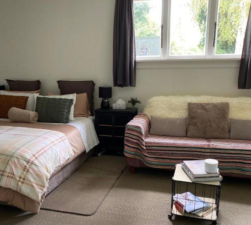 a bedroom with a bed and a couch and windows at Glenie Cottage BnB Guesthouse in Timaru