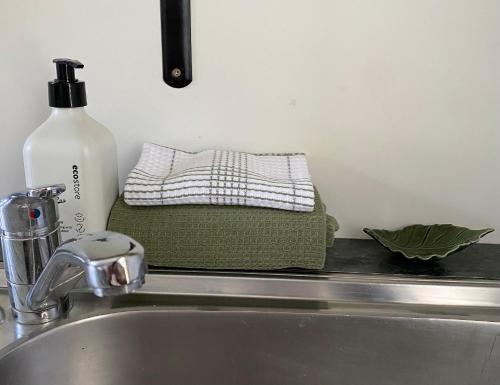 um lavatório com uma garrafa de sabão e uma toalha em Glenie Cottage BnB Guesthouse em Timaru