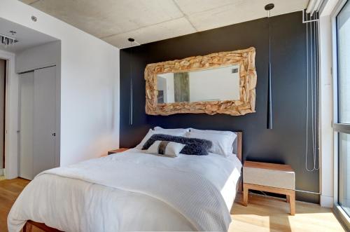 1 dormitorio con 1 cama grande y espejo en la pared en Les Immeubles Charlevoix - Le 760805, en Quebec