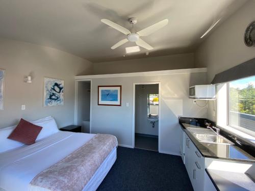 um quarto com uma cama, uma ventoinha de tecto e um lavatório. em LKNZ Lodge & Cafe em Ohakune