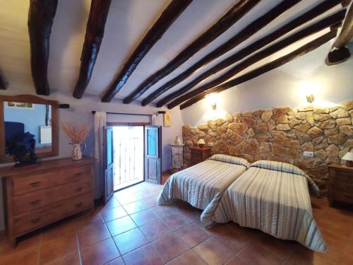 - une chambre avec un lit et un mur en pierre dans l'établissement Casa Roya, à Montalbán