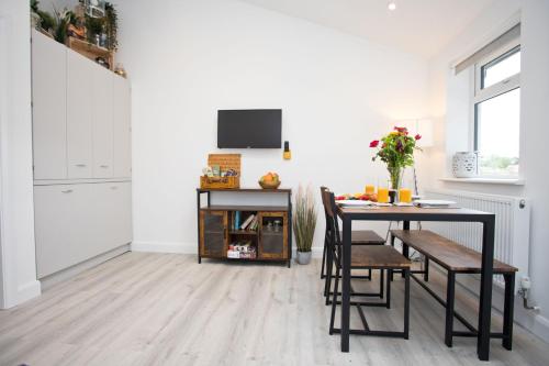 a dining room with a table and a tv on a wall at The Bearded Goat Den - A rural retreat at this modern holiday cottage in Saint Leonards