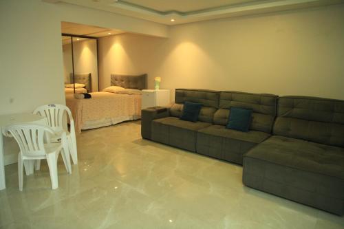 uma sala de estar com um sofá, uma mesa e uma cama em Valentina 24 HORAS em Florianópolis