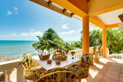 a table and chairs on a balcony overlooking the ocean at Villa 99-Beachfront-Pool-Luxury Villa in Placencia Village
