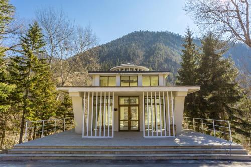 uma pequena casa branca nas montanhas em Borjomi Likani Health & Spa Centre em Borjomi
