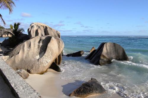 two large rocks in the water on a beach at Patatran Village Hotel in La Digue
