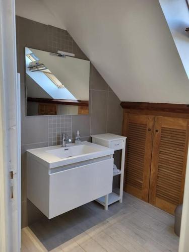 une salle de bain blanche avec un lavabo et un miroir dans l'établissement Le p'tit nid Bourian, à Concorès