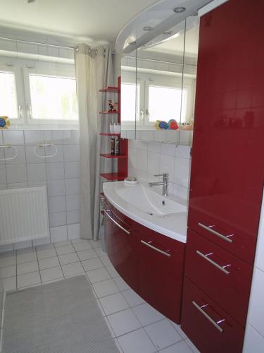 a bathroom with a sink and a red cabinet at Holiday Apartment Krumpendorf in Krumpendorf am Wörthersee