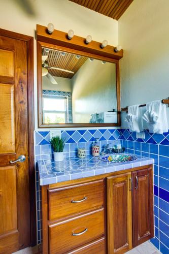 a blue tiled bathroom with a sink and a mirror at Villa 99-Beachfront-Pool-Luxury Villa in Placencia Village