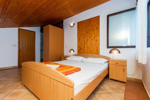 a bedroom with a large bed with a wooden headboard at Apartments Crljenko in Povljana