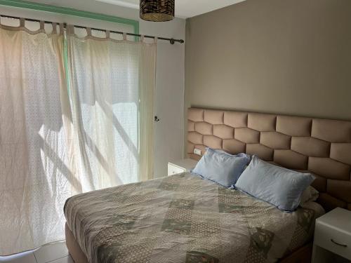 een slaapkamer met een bed met blauwe kussens en een raam bij Appartement City Jardin - Pied sur mer in Martil