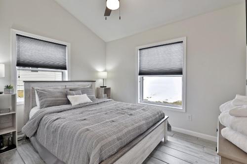 a white bedroom with a bed and two windows at Rutland's Hidden Gem- 2 BR 1BA Renovated Home Close to Everything home in Rutland