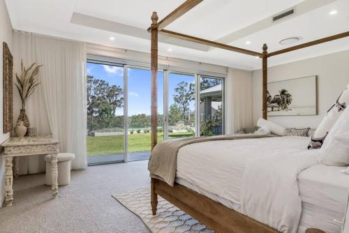 a bedroom with a large bed and a large window at Luxury Hunter Valley Estate in Lochinvar