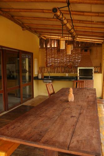 a large wooden table in a room with a kitchen at Casa do Imperador in Fernando de Noronha