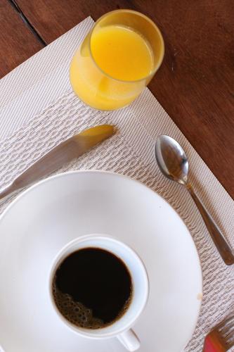 a cup of coffee on a table with a plate and a spoon at Casa do Imperador in Fernando de Noronha