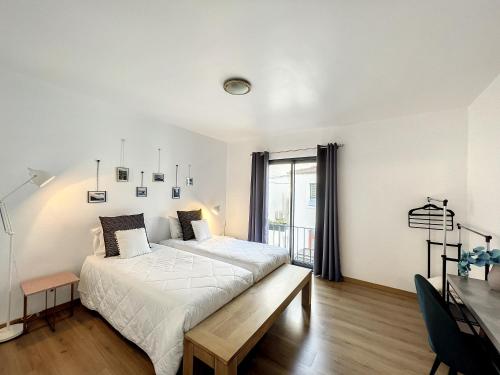 a white bedroom with a bed and a window at PIX Apartments in Madalena