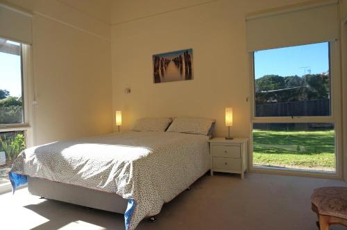 um quarto com uma cama com 2 candeeiros e 2 janelas em Rip Tide em Point Lonsdale