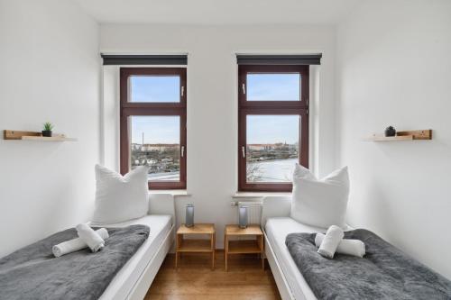 2 łóżka w białym pokoju z 2 oknami w obiekcie Apartment für 10 Gäste, 2 Bäder, 2 Loggia's, Leipzig Zentrum Ost w Lipsku