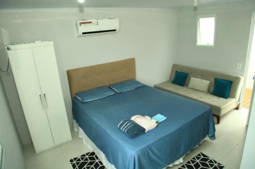 1 dormitorio con 1 cama azul y 1 sofá en Valentina 24 HORAS en Florianópolis